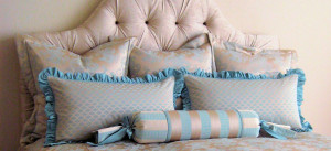 Tufted headboard with pillows created by Drapery Solutions.